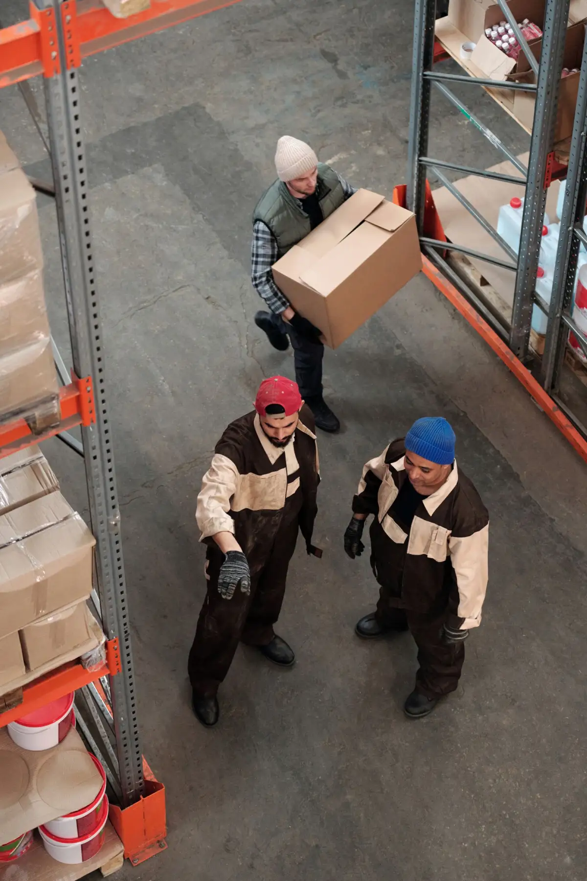 Warehouse team moving stock along an aisle of loaded shelving racks
