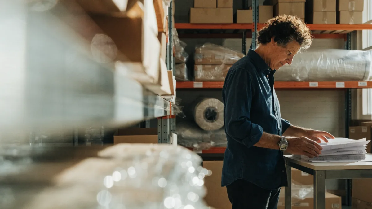 Warehouse business owner reviewing a stack of invoices