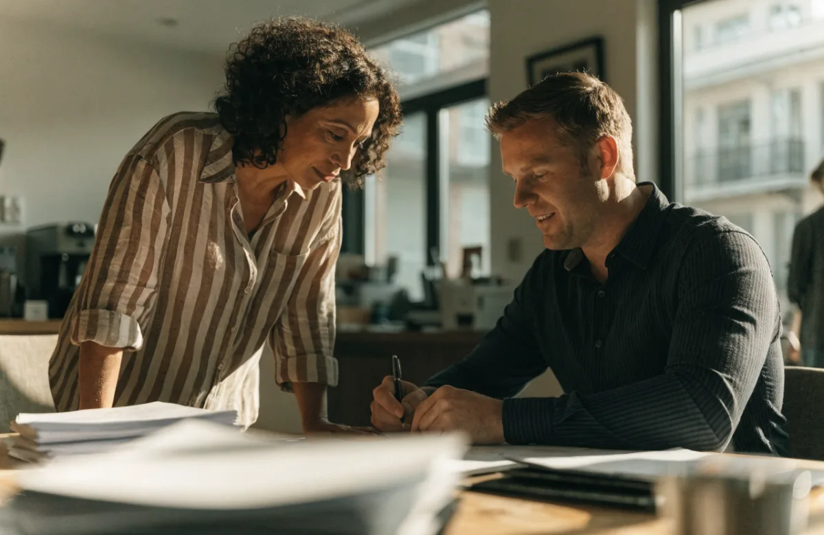 Business owner and finance adviser reviewing loan paperwork at a table