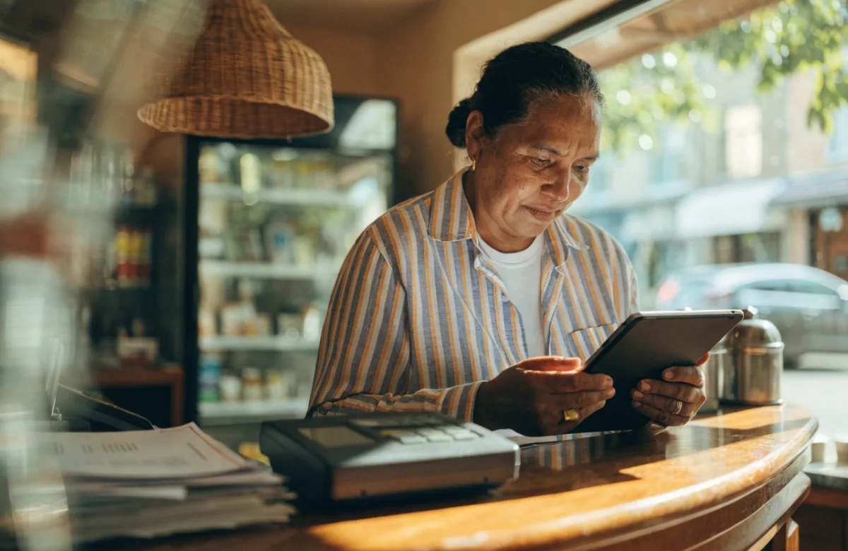 Shop owner reviewing figures on a tablet behind the counter