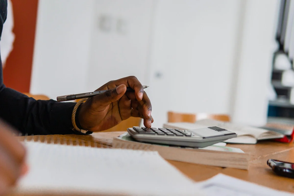Person going through paperwork with a pen and a calculator at a table