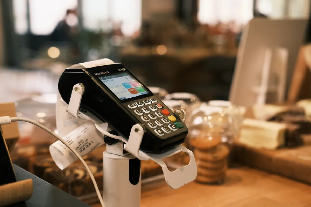 EFTPOS payment terminal on a café counter beside a printed settlement receipt
