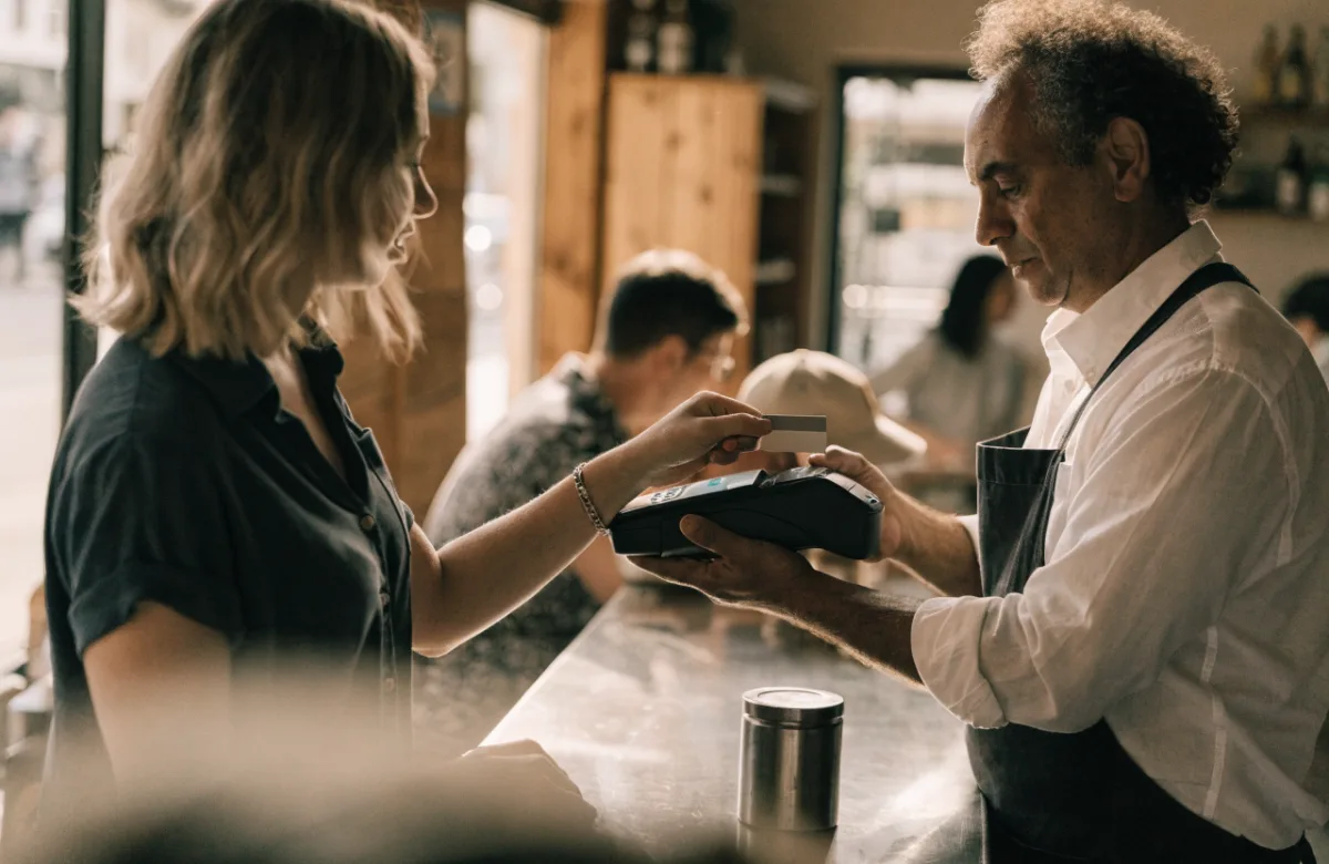 Customer tapping a card to pay at a café counter