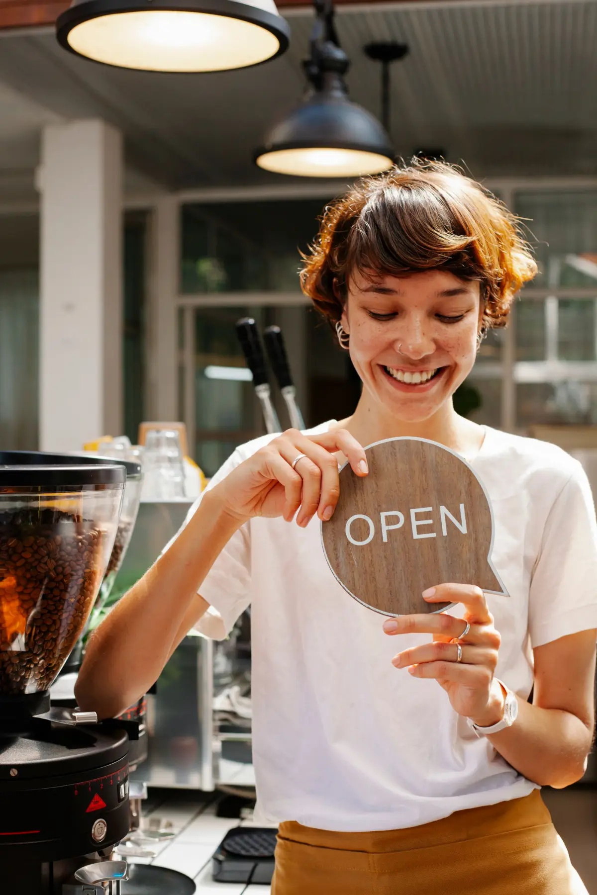 Small-business owner standing at her café door beside an open sign